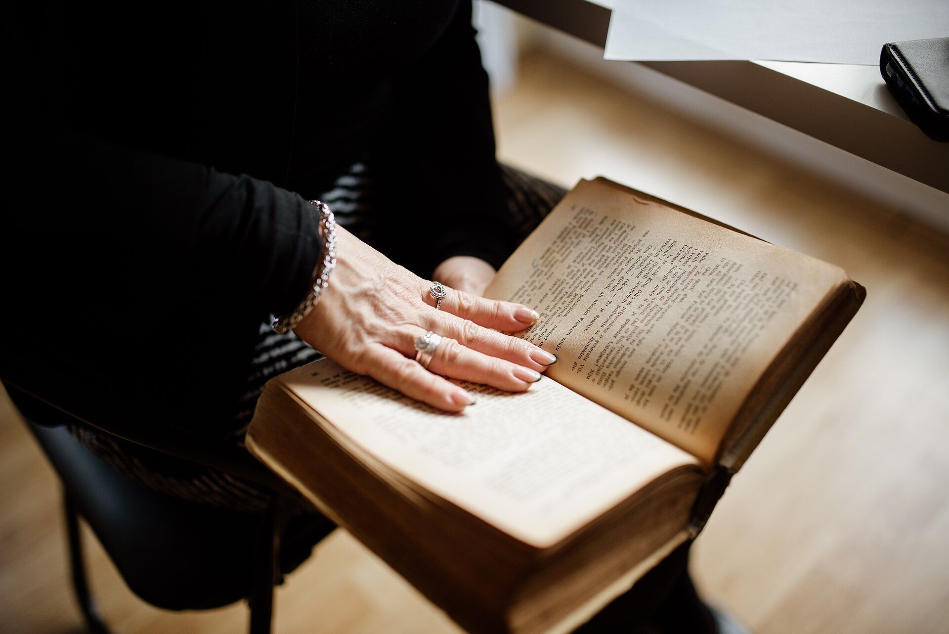 An older woman's hand resting on an open book.