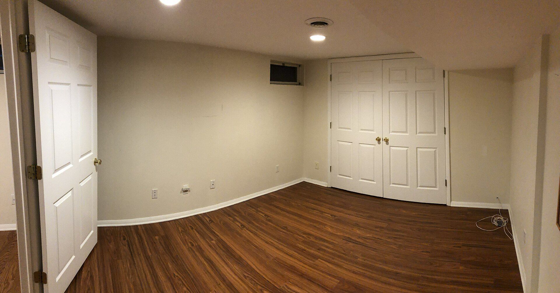 Une chambre vide dans un sous-sol fini, avec un plancher de bois.