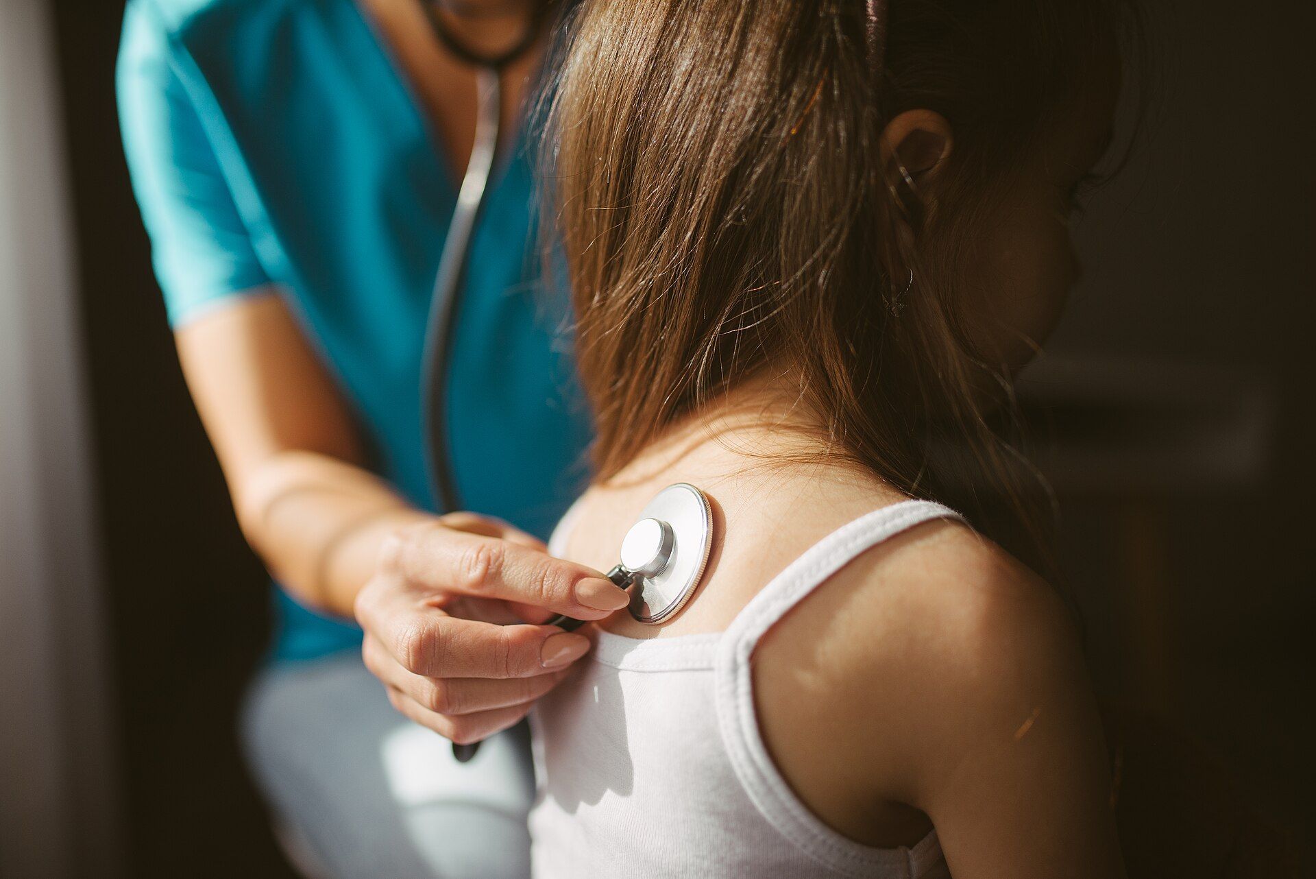 Un médecin écoute le dos d’un patient avec un stéthoscope.