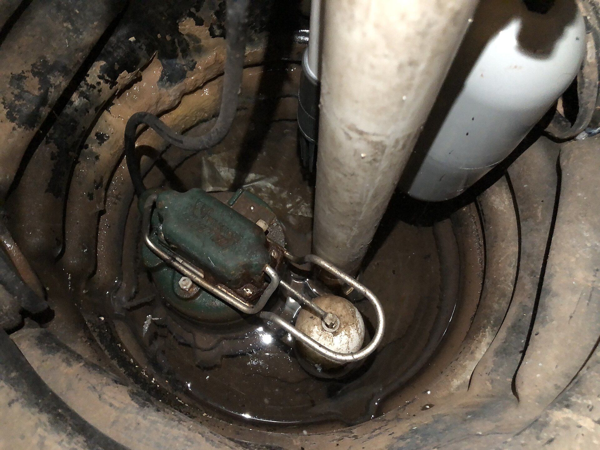 A new sump pump in a pit in a basement floor.