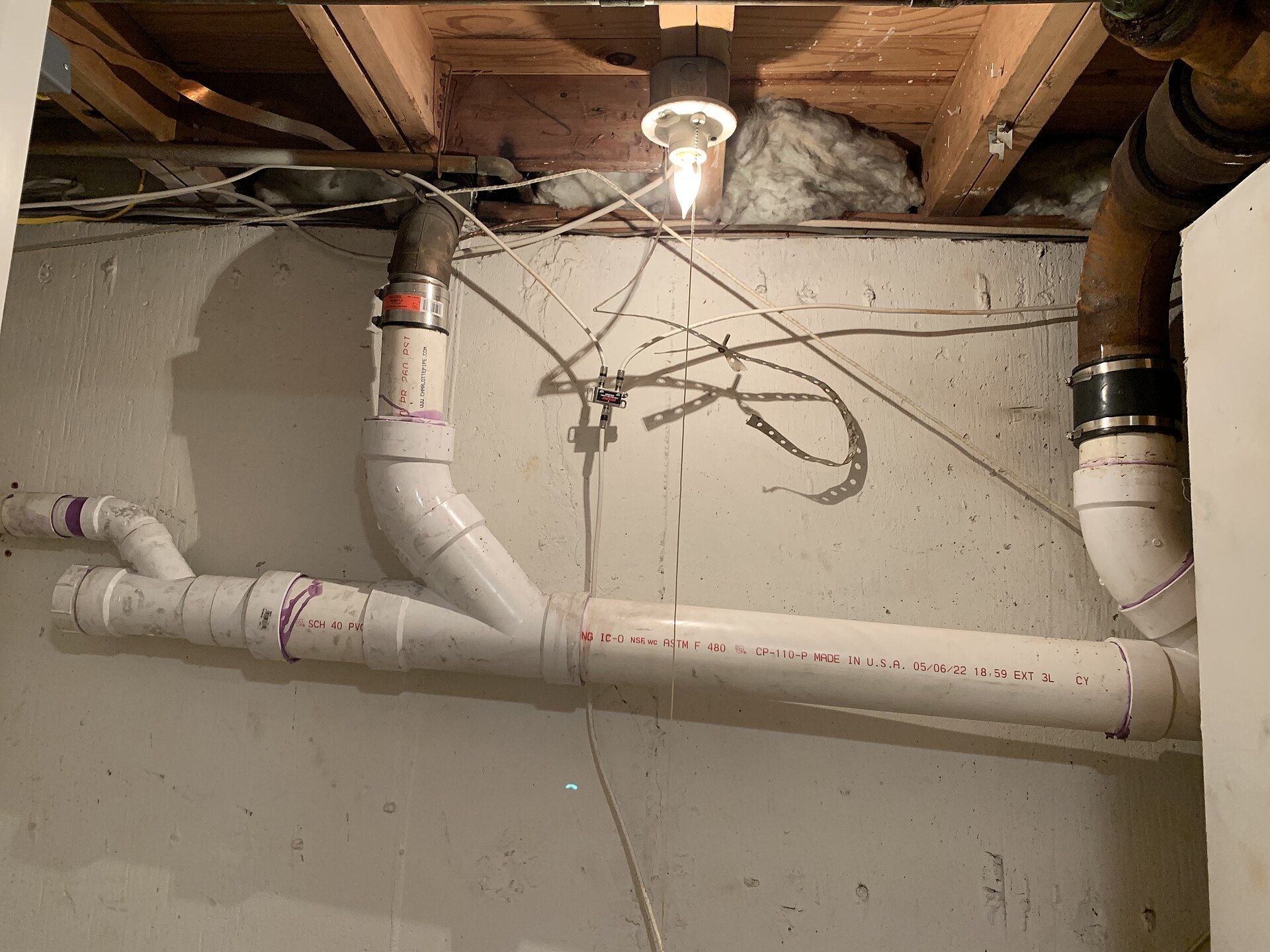 White plastic pipes in an unfinished basement.