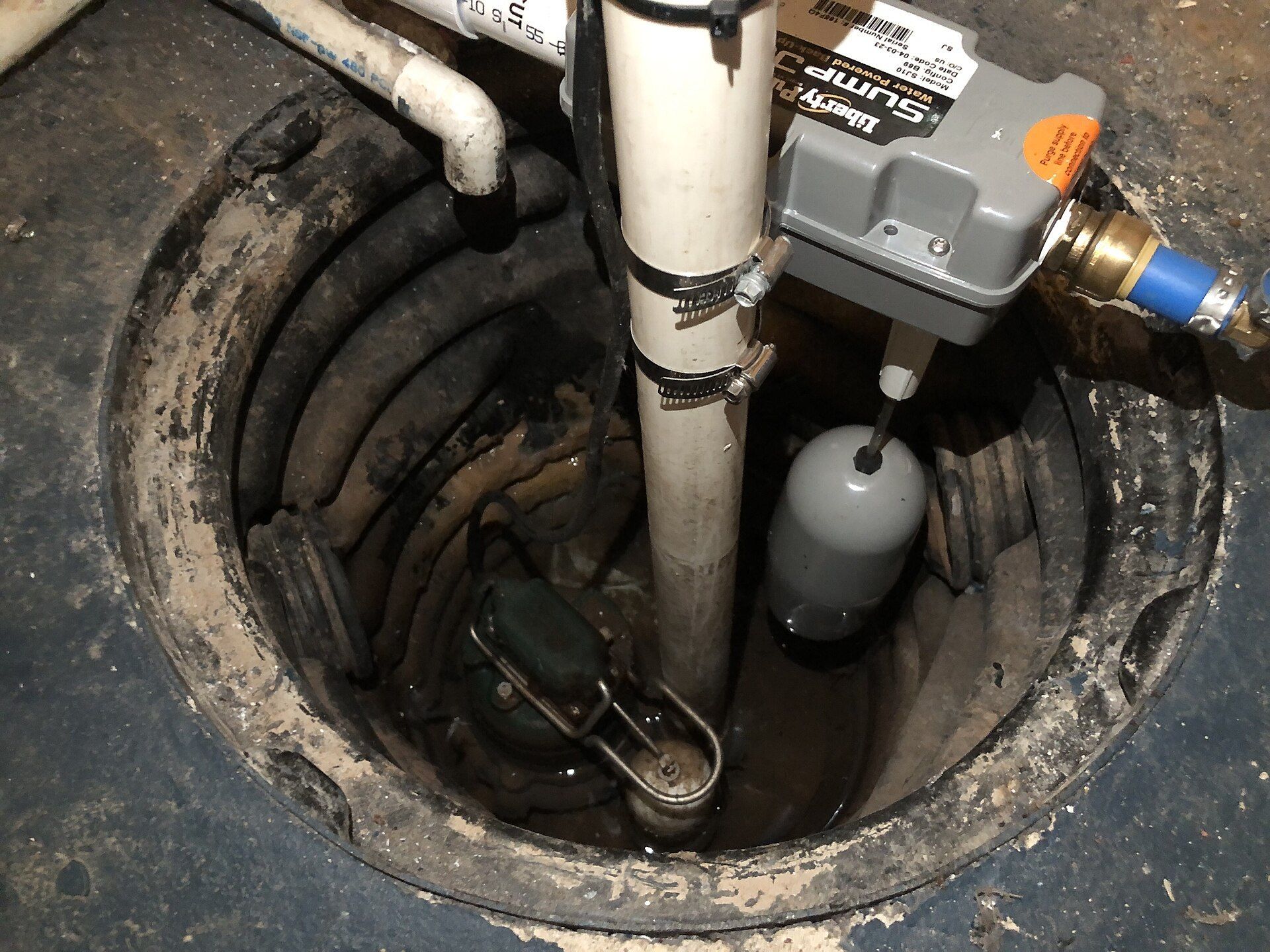 A sump pit in a basement floor, with its pipe running up out of it.