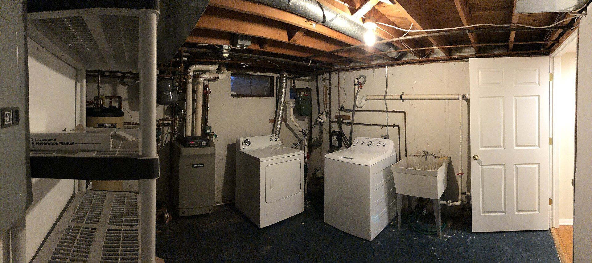An unfinished basement with a washer, dryer and furnace.