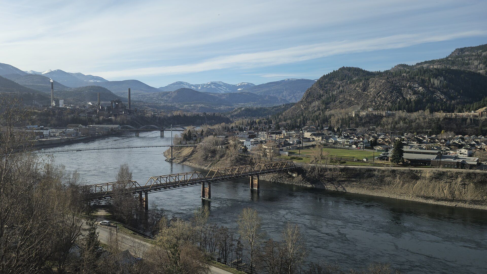 Trail, British Columbia, from above, with bridges over the Columbia River and the town and mountains behind.